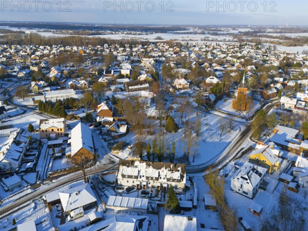 Snowy town view with many houses, a church and snow-covered roads, aerial view, Trinity church, Oelsburg, municipality of Ilsede, district of Peine, Lower Saxony, Germany