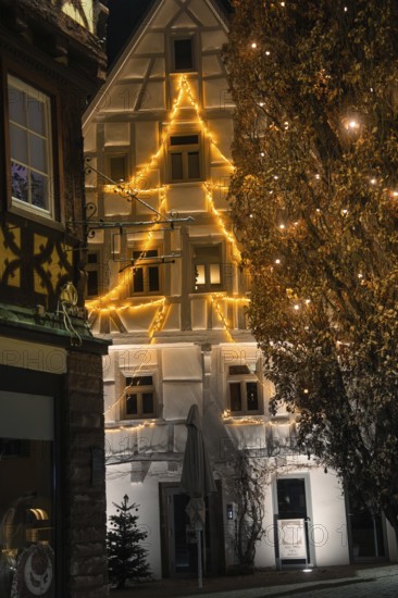 An old building is illuminated in warm lights for Christmas and gives the old town a festive light at night, Nagold, Calw district, Black Forest, Germany