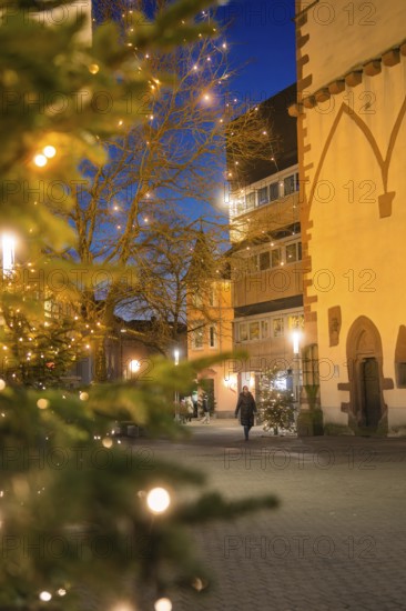 A Christmassy street with a single walker in front of historic buildings at dusk, Nagold, Calw district, Black Forest, Germany
