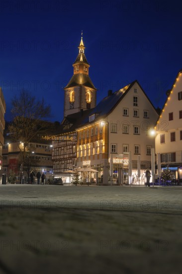 View of illuminated church tower and historic buildings in the evening darkness of the city, Nagold, Calw district, Black Forest, Germany