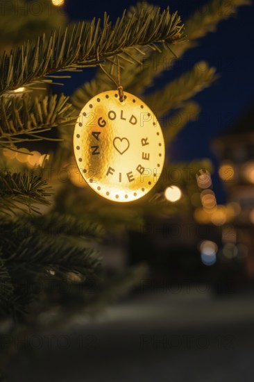 Small pendant with inscription on an illuminated pine branch outdoors, Nagold, Calw district, Black Forest, Germany