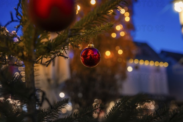 Close-up of a red Christmas ball on a tree, with blurred lights in the background, Nagold, Calw district, Black Forest, Germany