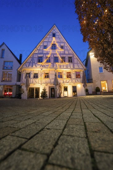Half-timbered house with Christmas tree-shaped fairy lights against evening sky, Nagold, Calw district, Black Forest, Germany