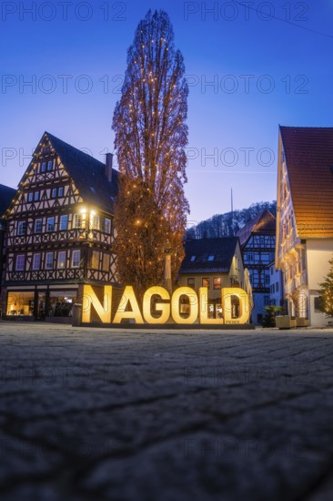 Nagold town center at dusk with illuminated lettering and half-timbered houses, Nagold, Calw district, Black Forest, Germany