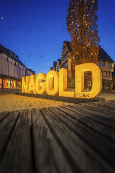 Illuminated Nagold lettering at dusk, surrounded by medieval buildings, Nagold, Calw district, Black Forest, Germany