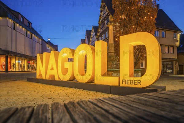 Large illuminated lettering 'Nagold' in an evening city promenade, modern architecture, Nagold, Calw district, Black Forest, Germany