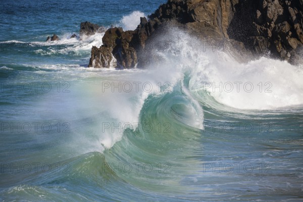 Waves crash against rocks at the mainland's easternmost point, creating rainbows in the ocean spray. Daylight, Byron Bay, New South Wales, Australia