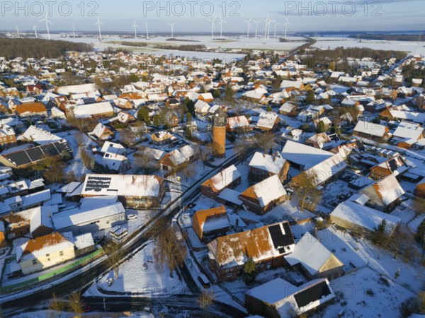 Snowy village with a water tower and a variety of wind turbines in the distance under a clear sky, aerial view, water tower, museum, Groß Lafferde, municipality of Ilsede, district of Peine, Lower Saxony, Germany