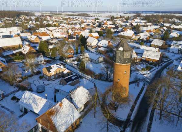 Winter village view with a distinctive water tower surrounded by snow-covered houses and distant wind turbines, aerial view, water tower, museum, Groß Lafferde, municipality of Ilsede, district of Peine, Lower Saxony, Germany
