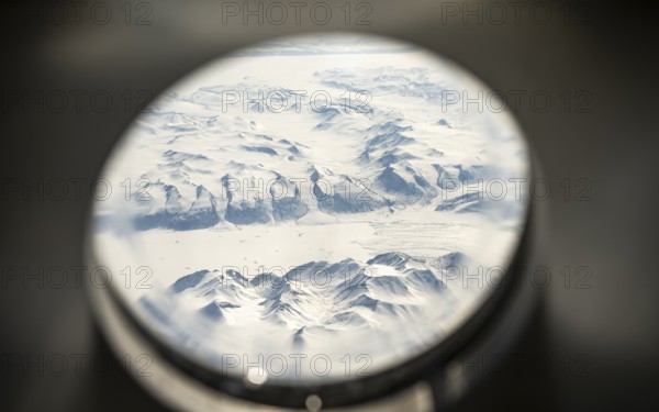 View from an airplane window of snowy arctic mountain landscape with glaciers, aerial view, Greenland, Arctic