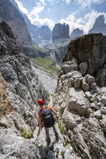 Mountaineers on a via ferrata in front of a picturesque mountain landscape with rocky peaks, Via Ferrata SOSAT via ferrata, Cima Tosa summit in the back, Brenta Mountains, Trentino, Italy