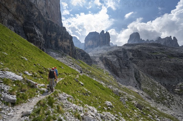 Two mountaineers on a hiking trail in front of a picturesque mountain landscape with rocky peaks, Via Ferrata SOSAT via ferrata, summit of Cima Tosa in the back, Brenta Mountains, Trentino, Italy