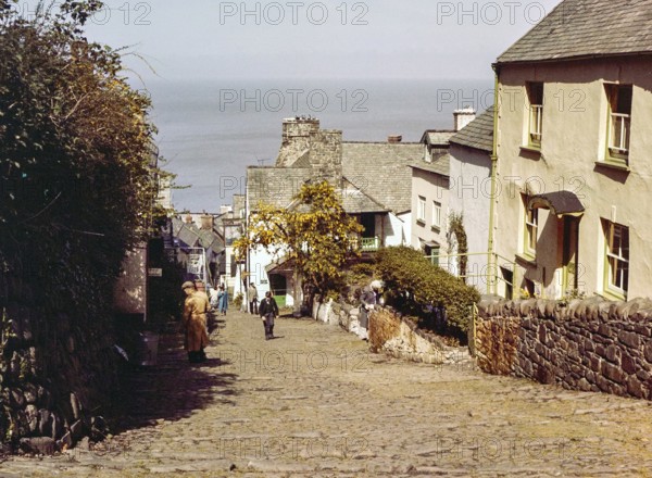 Steep hill of cobbled main street in coastal village of Clovelly, north Devon, England, UK 1960s