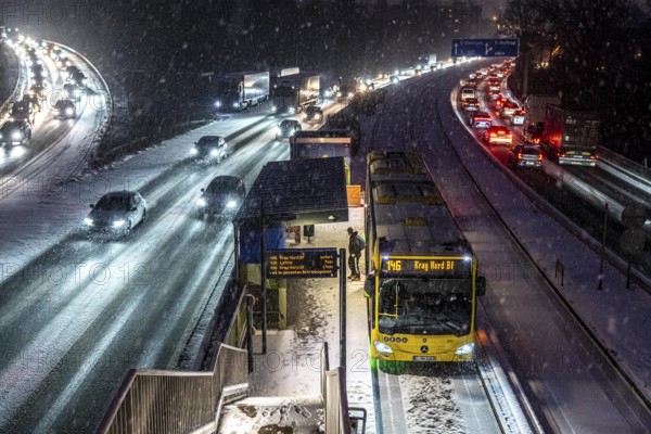 Winter weather, motorway traffic, A40 motorway, Ruhrschnellweg, in Essen, at the Essen-Ost motorway junction, snowfall, traffic jams, heavy flowing traffic, stop, bus lane between lanes, public transport, North Rhine-Westphalia, Germany