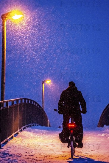 Winter weather, blowing snow, person with e-bike, bicycle on snowy bridge, footpath bridge, steep uphill, North Rhine-Westphalia, Germany