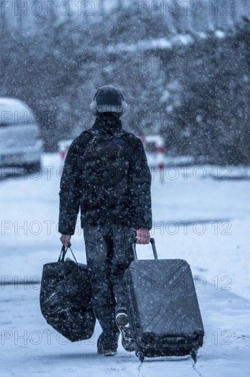 Winter weather, blowing snow, person with luggage on sidewalk, North Rhine-Westphalia, Germany