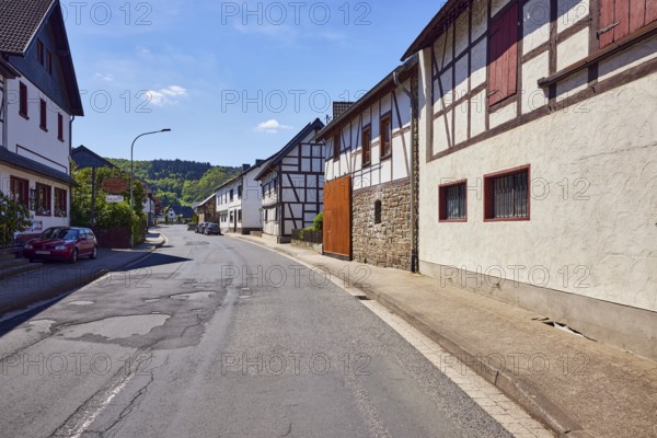 Residential and commercial buildings, historic half-timbered houses with sandstone base, lantern, hills, hilly landscape, forest, blue sky, cumulus clouds, cirrostratus clouds, street main street, Insul, Ahrweiler district, Rhineland-Palatinate, Germany