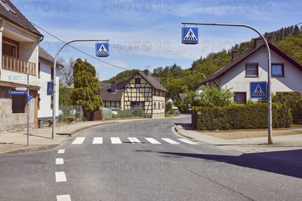 Pedestrian crossing, zebra crossing, traffic sign pedestrian crossing, residential building, historic half-timbered house, general architecture, sidewalk, street, trees, hills, forest, blue sky, cirrus clouds, cirrostratus clouds, intersection of main street, Brückenstraße and Kapellenweg, Insul, district of Ahrweiler, Rhineland-Palatinate, Germany