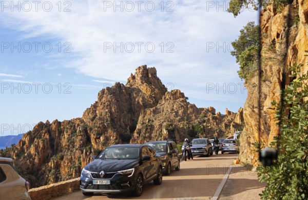 Bizarre rock erosion and car traffic, evening light, Calanche, Les Calanches de Piana, Corse-du-Sud, Corsica, France