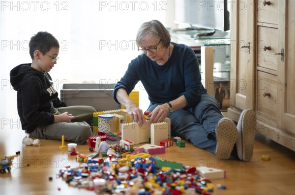 Elderly woman, grandma, boy, 6 years, grandson, glasses, multi-ethnic, playing together with Lego, concentrating, constructing, building, Stuttgart, Baden-Württemberg, Germany