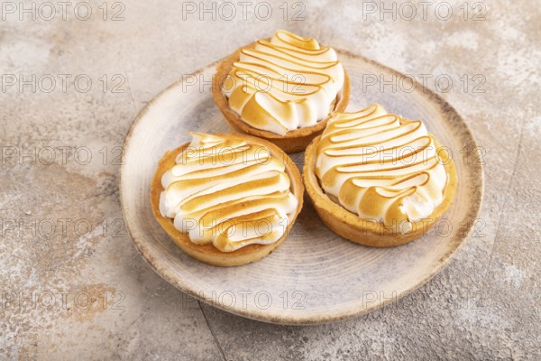 French lemon tart with meringue on brown concrete background, side view, close up
