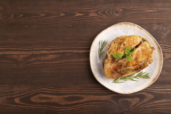 Fried Turkey Thigh with spices and rosemary on plate on brown wooden background. top view, flat lay, copy space