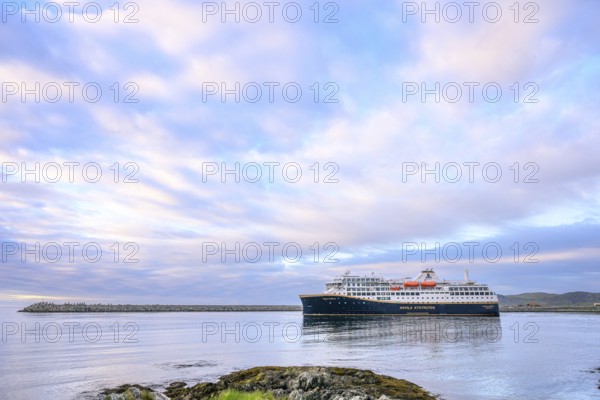 Cruise ship Havila Capella of Havila Kystruten competitor to Hurtigruten in Berlevag harbour, rocks in the foreground, quiet atmosphere, Berlevåg, Finnmark, Norway