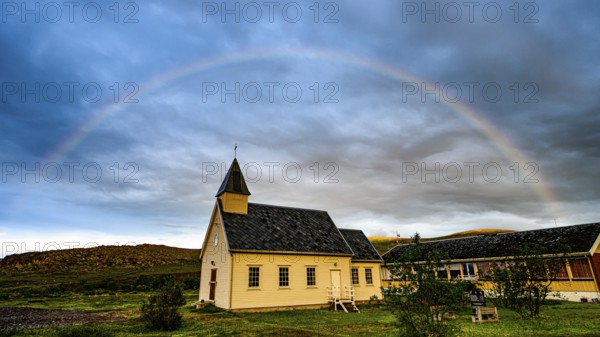 Nordford chapel on Ytre Syltefjord under a rainbow surrounded by cloudy sky, small church with rainbow in the sky, dramatic cloud formationsNordfjord, Båtsfjord, Finnmark, Norway