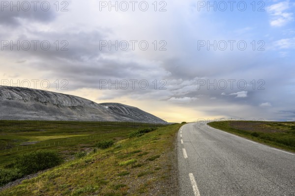 The Austertanaveien 890 winds through vast, quiet countryside, barren landscape with a winding road under a cloudy sky, Tana, Finnmark, Norway