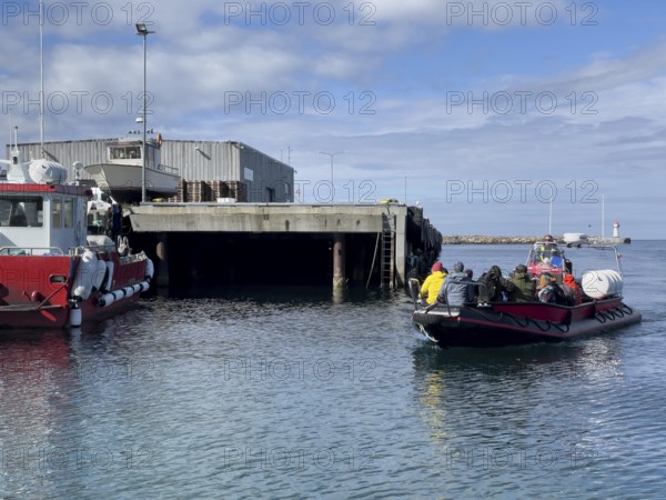 Port of the town of Vardö with the harbour master's ship and the incoming inflatable boat Speedboat taking tourists to the bird island of Hornoy, Vardø, Finnmark, Norway