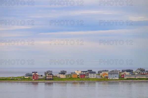 View of the port city of Vardø with a row of small colorful houses under blue sky with some clouds, Vardö, Finnmark, Norway