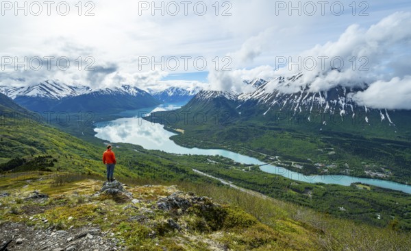 Climber enjoying the view, Slaughter Ridge Trail, view of snowy mountains and turquoise blue Kenai Lake, Cooper Landing, Kenai Peninsula, Alaska, USA