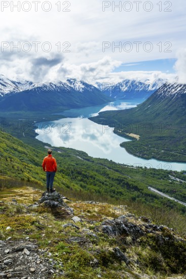 Climber enjoying the view, Slaughter Ridge Trail, view of snowy mountains and turquoise blue Kenai Lake, Cooper Landing, Kenai Peninsula, Alaska, USA