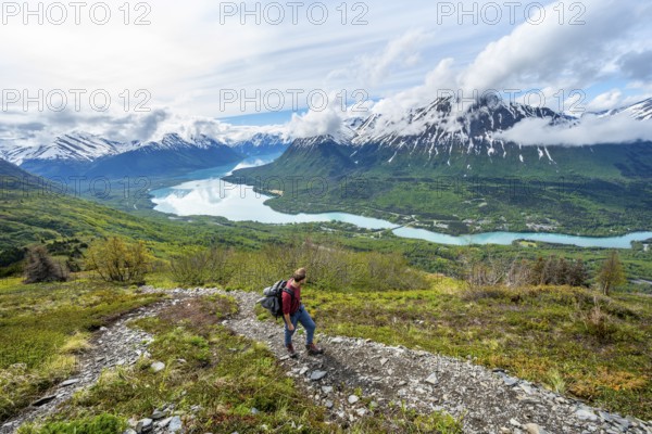 Climbers on a hiking trail, Slaughter Ridge Trail, view of snowy mountains and turquoise lake Kenai Lake, Cooper Landing, Kenai Peninsula, Alaska, USA