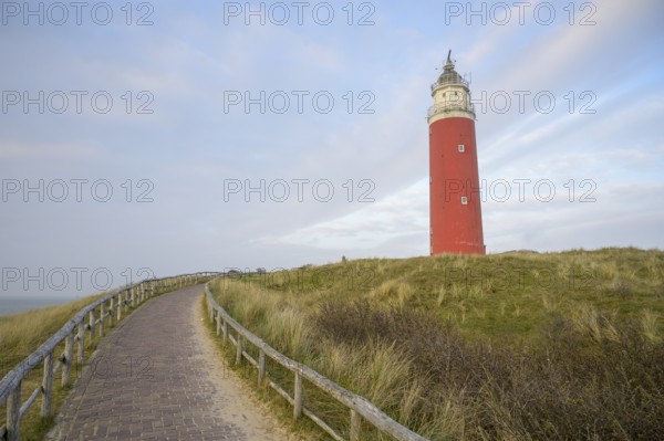 Red lighthouse of de Cocksdorp in the north of the island of Texel rises against the sky on grassy dunes, the Cocksdorp, Noord Holland, the Netherlands