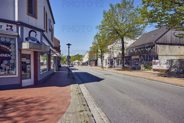Residential and commercial buildings, general architecture, retail stores, shops, shopping, lantern, trees with spring leaves, brick sidewalk, blue sky, cloudless, street main street, leak, Nordfriesland district, Schleswig-Holstein, Germany