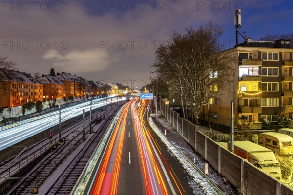 Autobahn A40, Ruhrschnellweg, near Essen at the Frohnhausen junction, evening traffic in winter, residential buildings directly on the 4-lane motorway, North Rhine-Westphalia, Germany