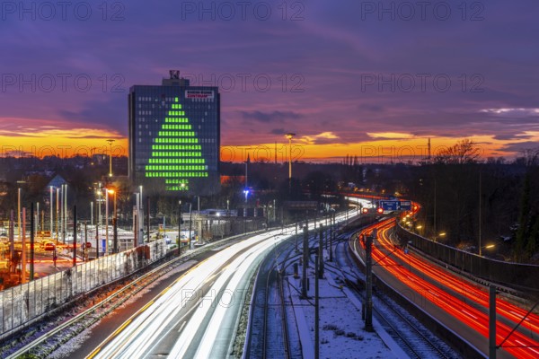 Autobahn A40, Ruhrschnellweg, between Essen and Mülheim an der Ruhr, evening traffic in winter, former, now vacant Stinnes high-rise building, at the Rhine-Ruhr Center, showing a green Christmas tree from illuminated windows at Christmas time, North Rhine-Westphalia, Germany