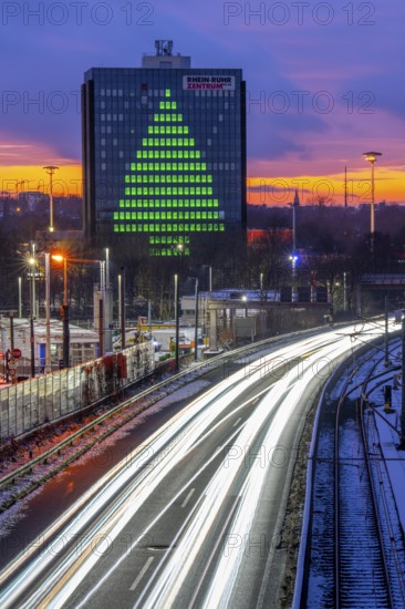 Autobahn A40, Ruhrschnellweg, between Essen and Mülheim an der Ruhr, evening traffic in winter, former, now vacant Stinnes high-rise building, at the Rhine-Ruhr Center, showing a green Christmas tree from illuminated windows at Christmas time, North Rhine-Westphalia, Germany