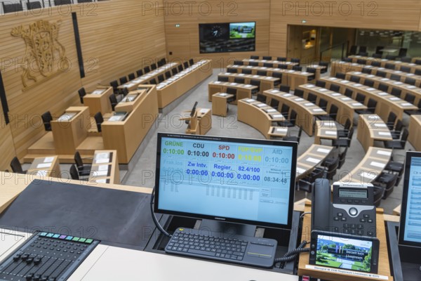 Plenary hall deserted with the seats of deputies and the government bank. Behind it is the country's coat of arms. The speaking time of members of the parties is recorded and documented down to the second. The state parliament of Baden-Württemberg is the state parliament based in Stuttgart, Baden-Württemberg, Germany