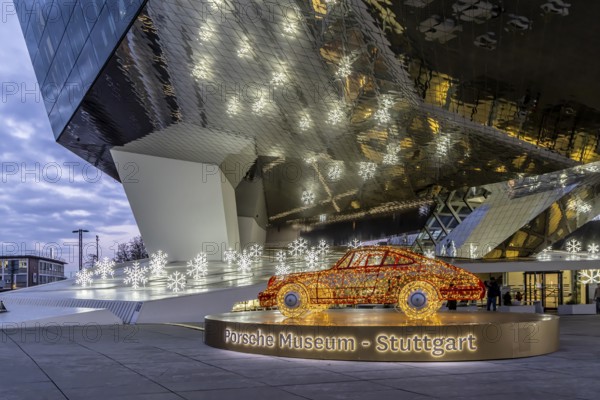Highlights on Porscheplatz in Zuffenhausen. In front of the Porsche Museum and the car manufacturer's headquarters, a 911 sports car shines in Christmassy splendor. Stuttgart, Baden-Württemberg, Germany