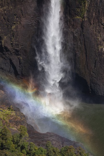 Daytime top view at Wallaman Falls with rainbow in mist over cascading water, Queensland, Australia