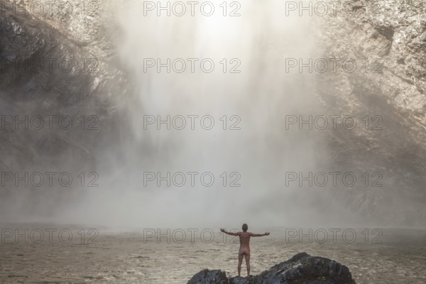 Daytime scene at Wallaman Falls with a fit man, nacked, below the waterfall, Queensland, Australia