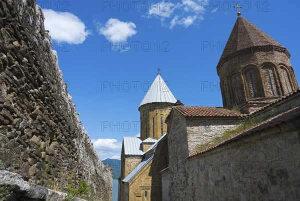 Historic monastery complex with brick towers and a surrounding stone wall under a blue sky, Ananuri Castle, Zhinvali Reservoir, Jinvali or Shinvali, Mtskheta-Mtianeti Region, Georgian Military Road, Georgia