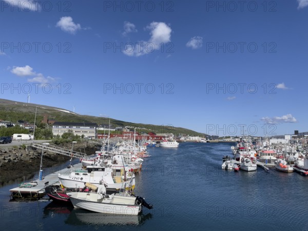 Several fishing boats and boats with outboards in Batsfjord harbour, blue sky, mountains in the background, sunny day, Båtsfjord, Finnmark, Norway