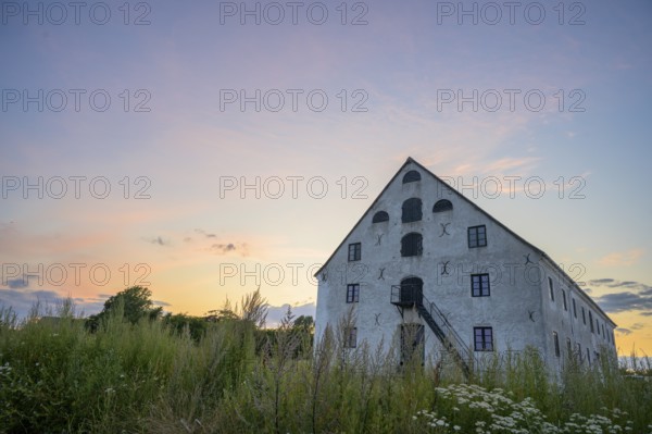 A historic stone building under a colorful evening sky at sunset, old merchant magazine, Südpunkt Sweden, Skane län, Sweden