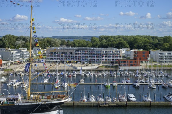 Harbour view with the legendary four-masted PASSAT barque and many boats in front of modern buildings under blue skies, Travemünde, Lübeck, Schleswig-Holstein, Germany