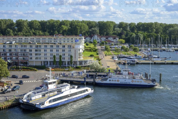 Ferries across the river Trave to Priwall in a busy small port in the town of Travemünde with surrounding buildings and yachts, Travemünde, Lübeck, Schleswig-Holstein, Germany
