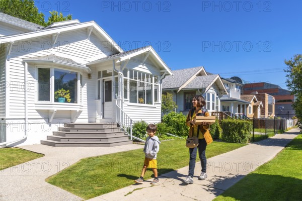 Mother and son are walking back home after picking up a food delivery order on a sunny summer day in a residential neighborhood of calgary, alberta, canada