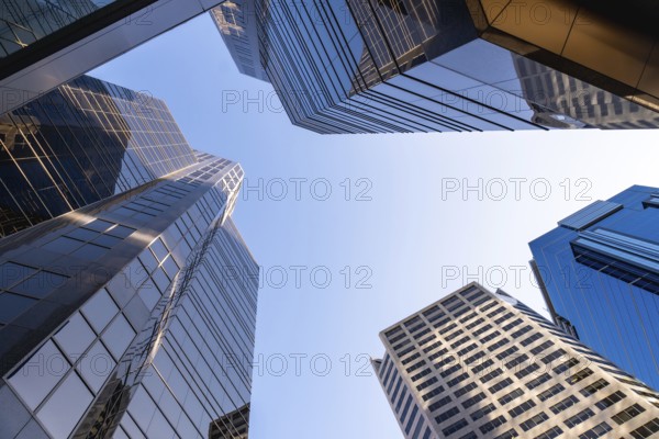 Low angle view of modern skyscrapers in calgary, canada, emphasizing their height and contemporary design against a clear blue sky, symbolizing urban growth